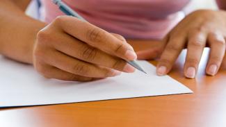 A student writing a bursary application letter, requesting funding.