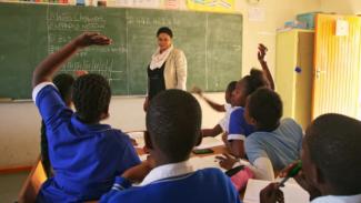 A teacher addresses a class of students in school uniform