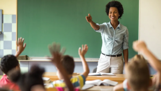 a teacher points to a student with their hand raised up