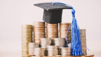 stacks of coins with a miniature graduation cap on top of the stack
