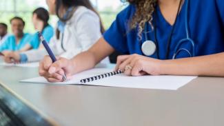 A nursing student writes notes in a classroom
