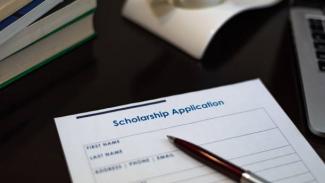 A fill-in scholarship application form and a pen on a table