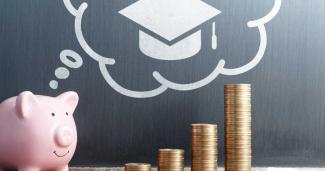 a piggy bank and some coins in front of a chalk board with a speech bubble that has a graduation cap in it