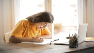 Female student wearing a yellow t-shirt sitting at desk