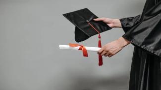 Student holding graduation cap and diploma 