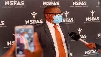 blade nzimande in front of a nsfas banner