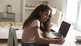 student writing online nbt exam from her room