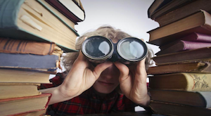 Gap Year student with binoculars in between piles of books